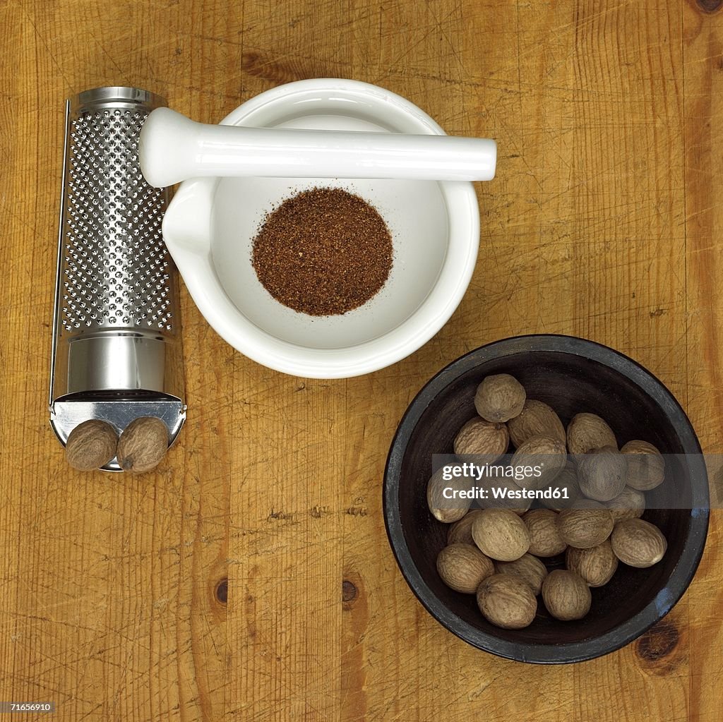 Nutmegs in bowl with mortar and grater, close-up