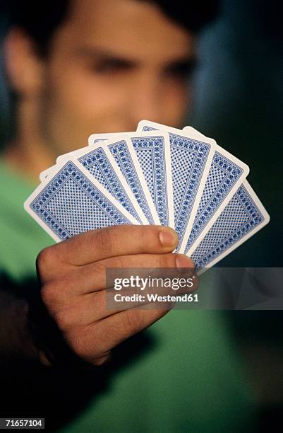 young man holding playing cards, focus on cards at foreground, close-up - hand of cards - fotografias e filmes do acervo