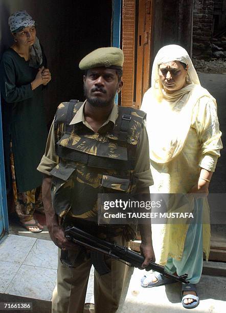 Kashmiri Muslim women watch as an Indian Central Reserve Police Force soldier stands alert during a cordon and search operation at Kukar Bazar in...