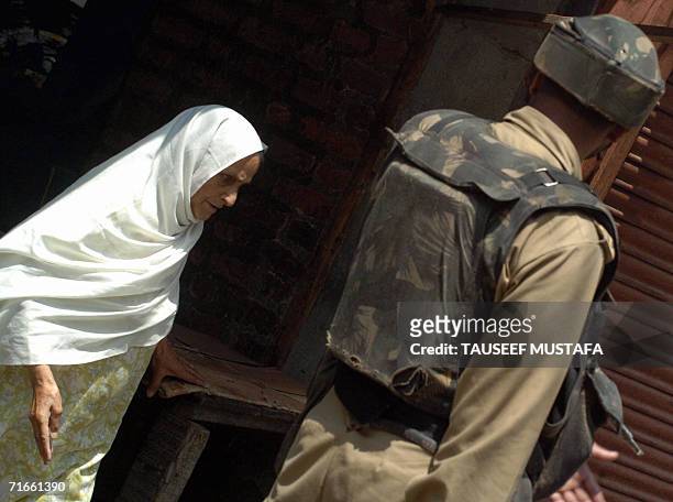 Kashmiri Muslim woman walks past an Indian Central Reserve Police Force soldier during a cordon and search operation at Kukar Bazar in Srinagar, 17...