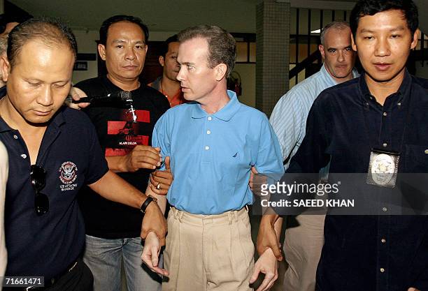 Thai police officials escort away US teacher John Mark Karr at the Thai Immigration Department in Bangkok, 17 August 2006. Police said 17 August that...