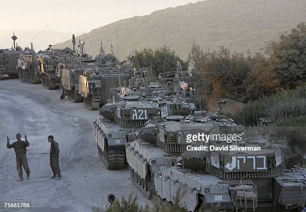 Israeli soldiers walk past tanks and armored personnel carriers after their return from an early morning patrol in southern Lebanon to a forward base...