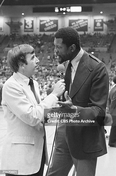 American sportscaster Brent Musburger interviews former professional basketball player and head coach Bill Russell on the court during a basketball...