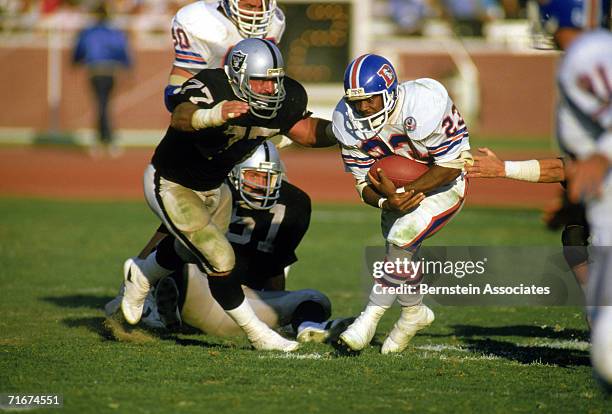 Running back Sammy Winder of the Denver Broncos carries the ball as Lyle Alzado of the Los Angeles Raiders moves to tackle during a 1984 season game...