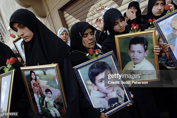 Women hold portraits of dead children, as most of the civilian victims of an Israeli air strike are formally buried August 18, 2006 in Qana, Southern...