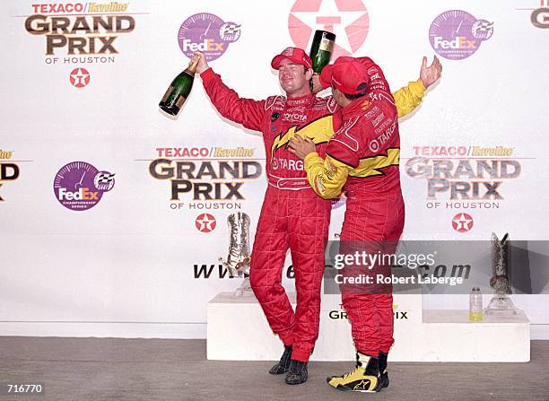 Driver Jimmy Vasser of the USA gets champagne poured down his suit by Driver Juan Montoya of Columbia after winning the Texaco Grand Prix of Houston,...