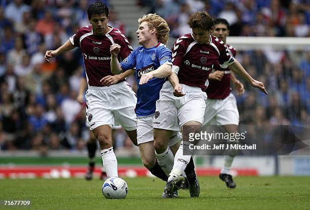 Chris Burke of Rangers gets tackled by Takis Fyssas and Saulius Mikoliunas of Hearts during the Scottish Premier League match between Rangers and...