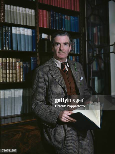 British Conservative Party politician and Secretary of State for Foreign Affairs, Anthony Eden posed standing next to a bookcase in his office circa...