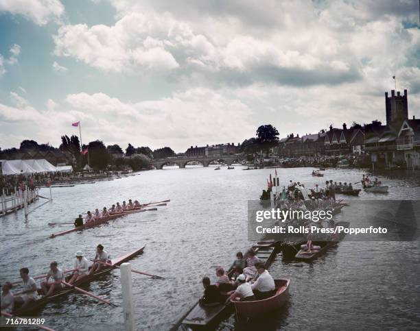 View of spectators watching a pair of coxed eight rowing boats on the River Thames at Henley-on-Thames as they compete in the Henley Royal Regatta in...