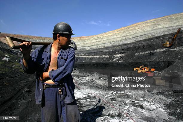 Coal miner walks on coal seams in an open pit coal mine on August 19, 2006 in Chifeng of Inner Mongolia Autonomous Region, China. Pingzhuang Coal...