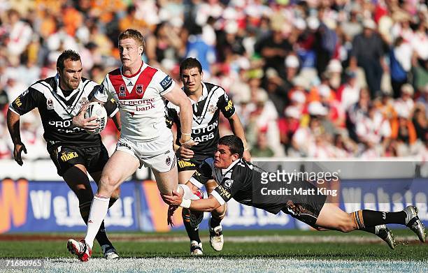 Ben Creagh of the Dragons evades the tackle of Chris Heighington of the Tigers during the round 24 NRL match between the St. George Illawarra Dragons...