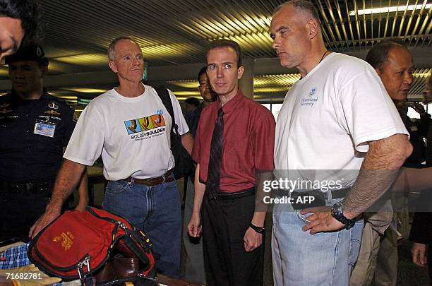 Security officials keep an eye on US teacher John Mark Karr during his luggage check prior to boarding a plane for the US in Bangkok, 20 August 2006....