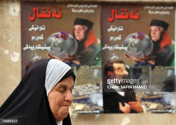 An Iraqi Kurdish elderly woman walks past at a poster in the northern city of Arbil 19 August 2006 announcing ousted Iraqi President Saddam Hussein's...