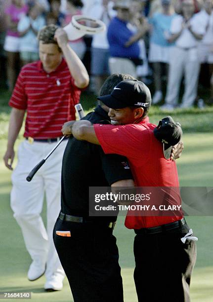 Medinah, UNITED STATES: Tiger Woods of the United States is congratulated by his caddie Steve Williams on the 18th hole after sinking the winning...