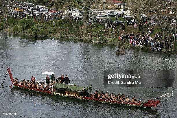 Crowds of people watch from the river bank as the late Queen Dame Te Atairangikaahu lays in the waka and travels down the Waikato river on August 21,...