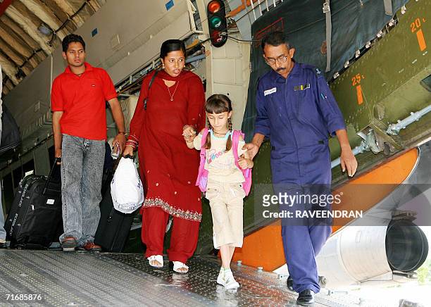 An Indian family are escorted by an Indian Air Force officer down a gangway at the rear of an IAF IL-76 cargo relief supply aircraft at Palam Air...