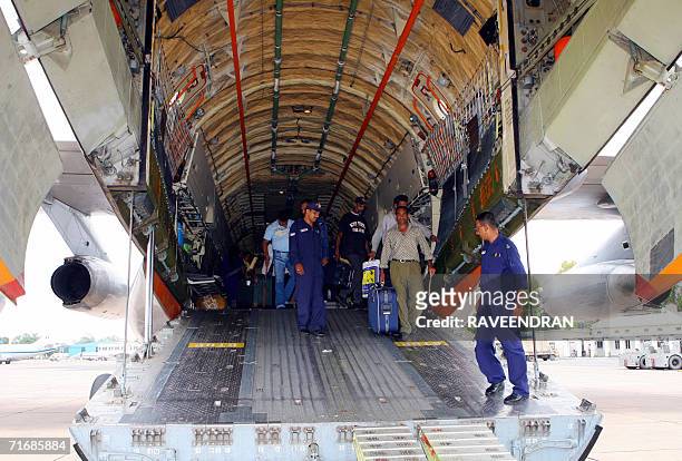 Indian workers are escorted by Indian Air Force officers down a gangway at the rear of an IAF IL-76 cargo relief supply aircraft at Palam Air Force...