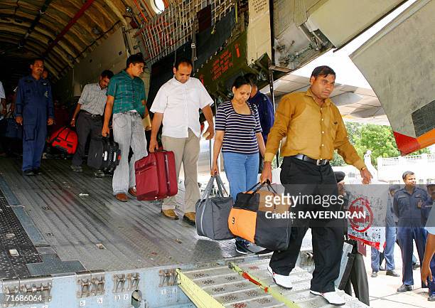 Indian workers walk down a gangway at the rear of an IAF IL-76 cargo relief supply aircraft at Palam Air Force Station in New Delhi, 21 August 2006,...