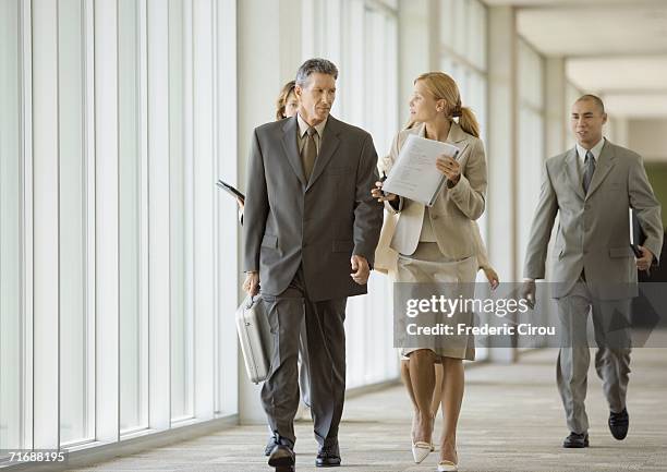 executives walking through corridor of office building - hierarquia de corporação imagens e fotografias de stock