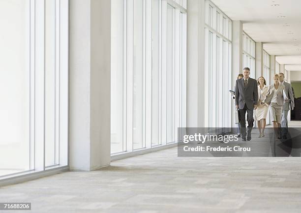 executives walking through corridor of office building - ir em frente imagens e fotografias de stock