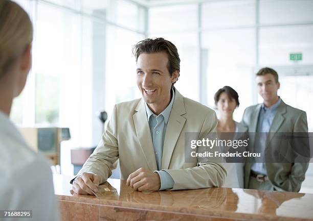 man standing at reception desk - leaning on elbows stock pictures, royalty-free photos & images