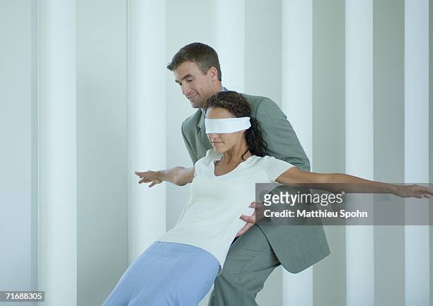 businessman catching blindfolded woman - reliable fotografías e imágenes de stock