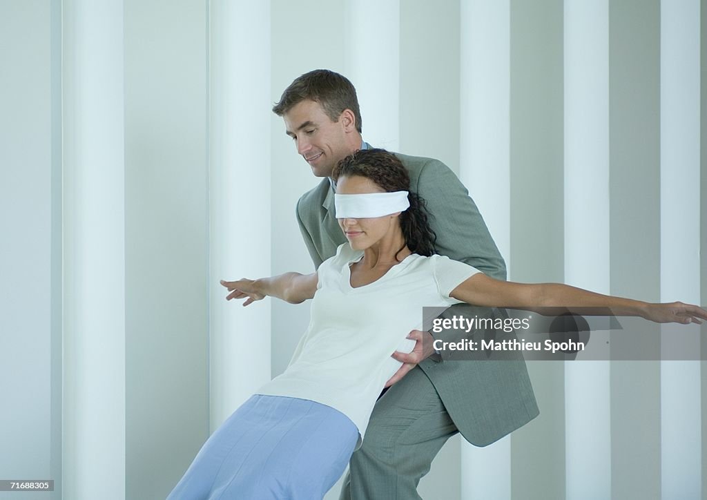 Businessman catching blindfolded woman