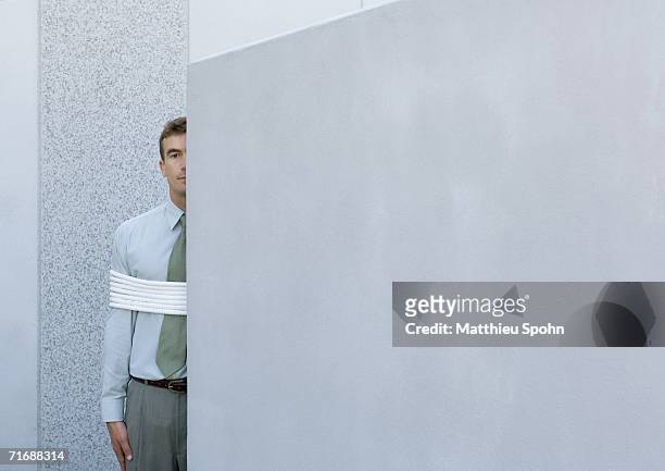 businessman tied up, standing partially hidden behind wall - hostage stock pictures, royalty-free photos & images