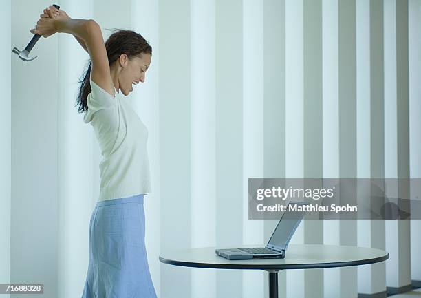 woman shouting and swinging hammer at laptop - technofobie stockfoto's en -beelden