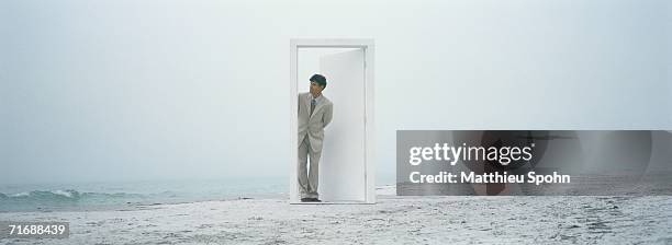 businessman coming through doorway on beach - fehl am platz stock-fotos und bilder