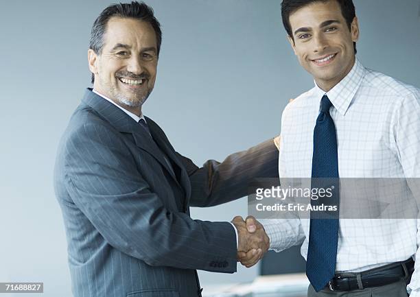 business executives shaking hands, smiling at camera - handshake business zwei personen stock-fotos und bilder