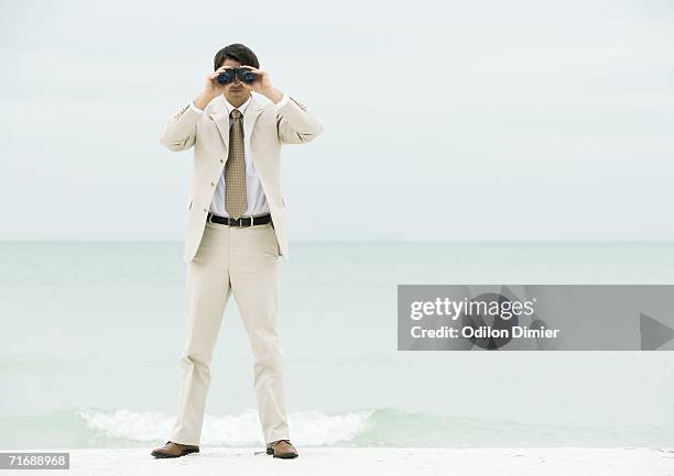 businessman looking through binoculars, facing camera - vouyer stock pictures, royalty-free photos & images