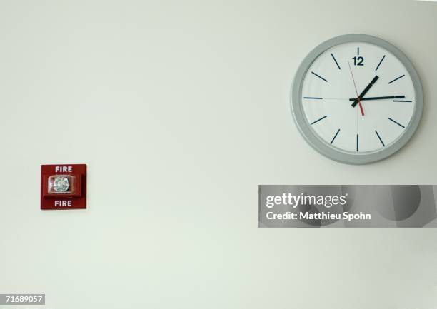 clock and fire alarm on wall - relógio de parede imagens e fotografias de stock