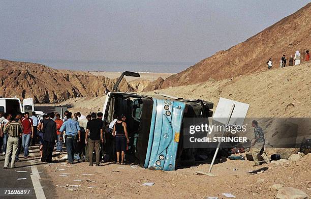People stand around an overtuned bus near Saada, about 45 kilometres north of Nuweiba, Egypt 22 August 2006. At least 11 people were killed when the...