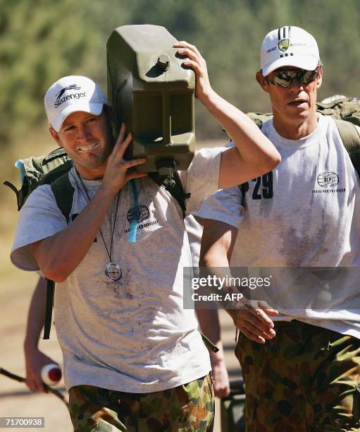 Michael Clarke of Australia carries a jerry can of water as coach John Buchanan looks on during an outback boot camp training session in the Beerwah...