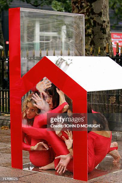 United Kingdom: Three contortionists squeeze into a small perspex house in Leicester Square in central London, 24 August in a protest organised by...