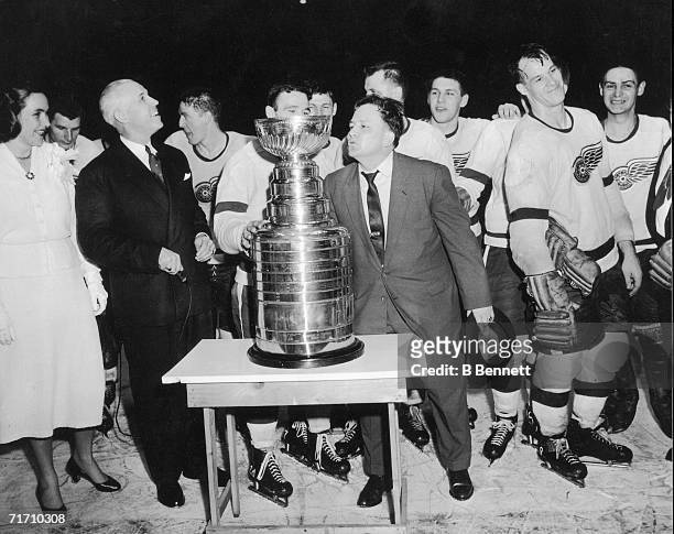Head coach Jimmy Skinner of the Detroit Red Wings holds his hat in his hand as he leans in to kiss the Stanley Cup trophy after his team won,...