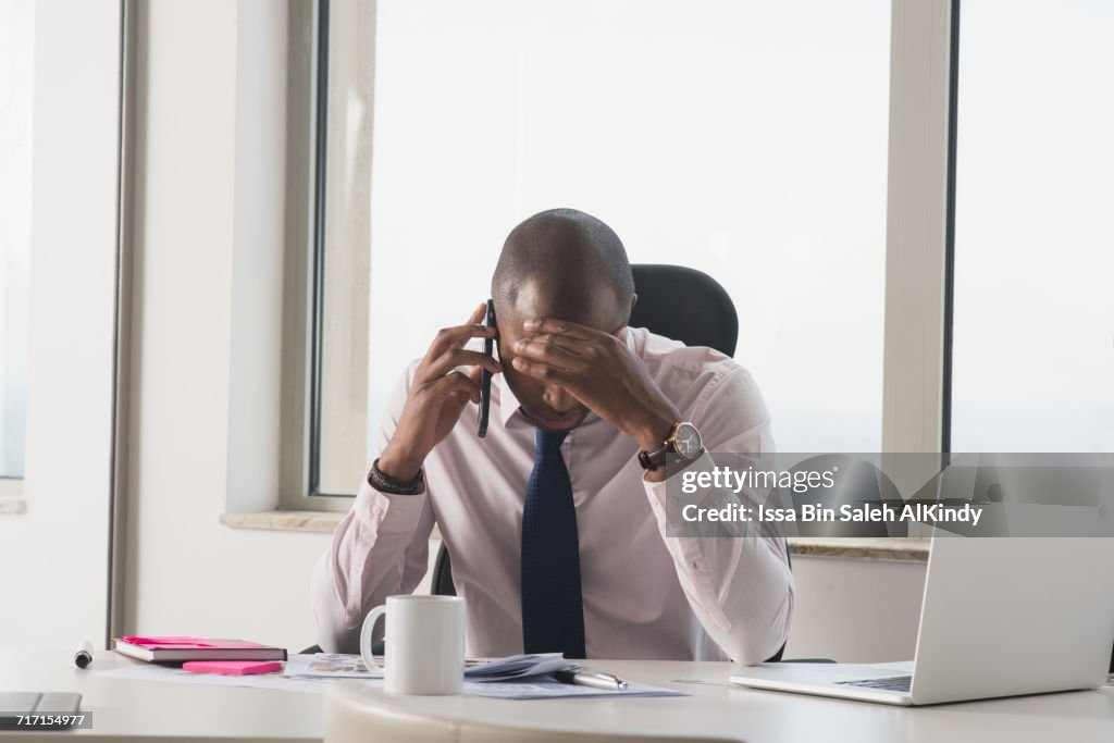 African businessman with head in hand at the office