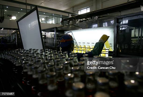 Worker inspects the bottles of Tsingtao beer before they are shipped out of the brewery at the Tsingtao beer factory on August 25, 2006 in Qingdao,...