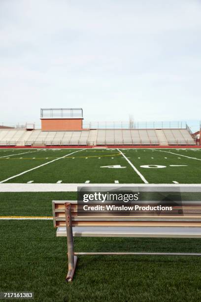 american football field with bench in foreground and empty bleachers in background - american football stadium background fotografías e imágenes de stock