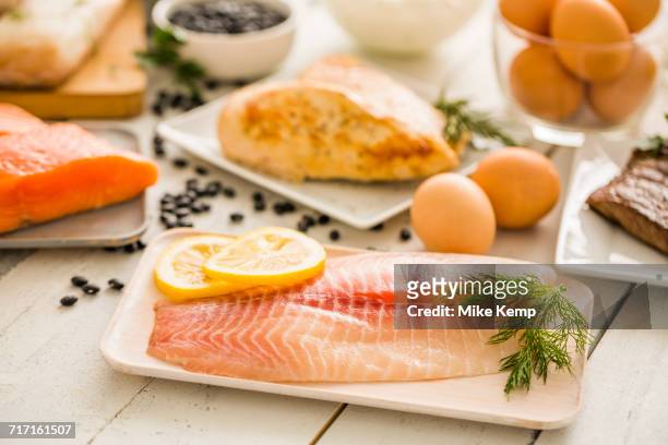 raw tilapia fish on plate, chicken and eggs in background - tilapia stock pictures, royalty-free photos & images