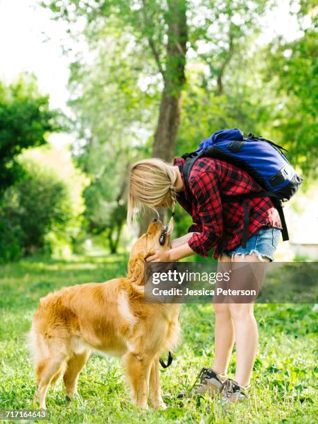 young woman playing with golden retriever - inarcare la schiena foto e immagini stock