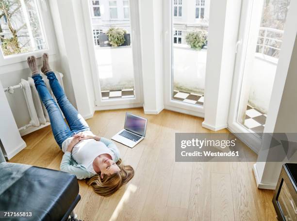 woman at home lying on the floor next to laptop - feet up stock pictures, royalty-free photos & images