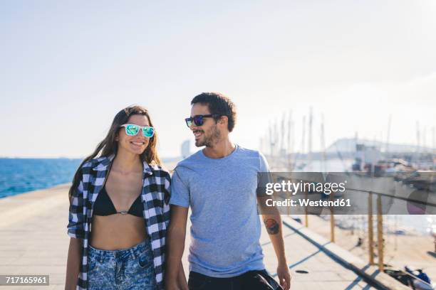 happy young couple walking at the harbour - cabello-castaño fotografías e imágenes de stock
