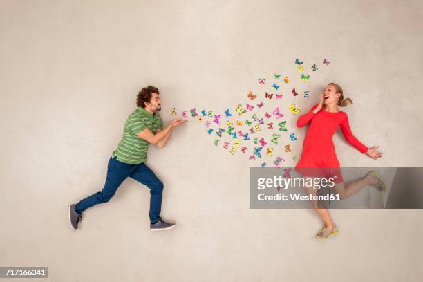 young man blow-kissing butterflies to a woman - quirky kissing foto e immagini stock
