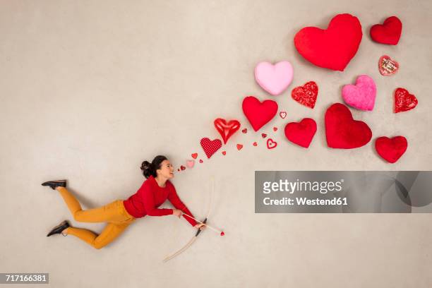 woman with bow and arrow and hearts around - arco y flecha fotografías e imágenes de stock