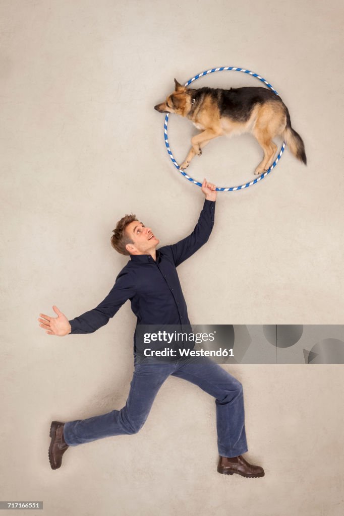 Man training his dog to jump through a hoop