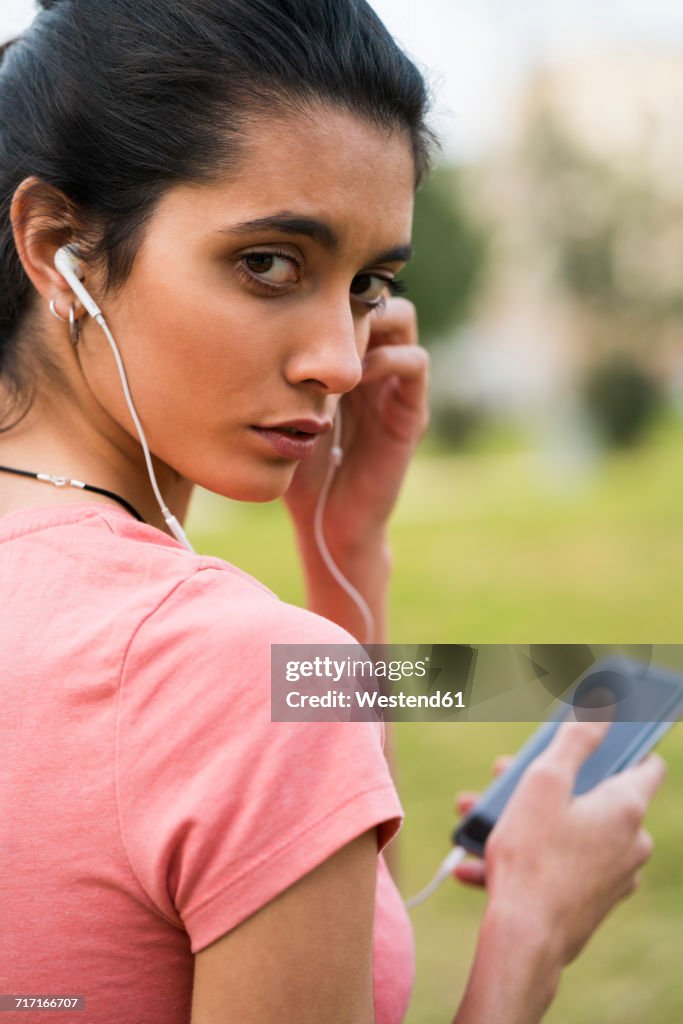 Portrait of female athlete with earphones and cell phone