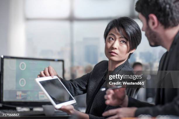 woman showing tablet to colleauge in city office - disappoint bussiness meeting stock pictures, royalty-free photos & images