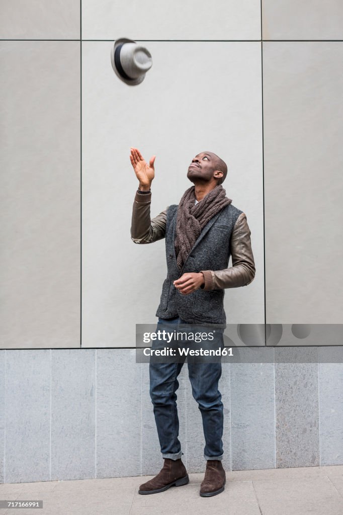 Stylish young man throwing his hat in the air